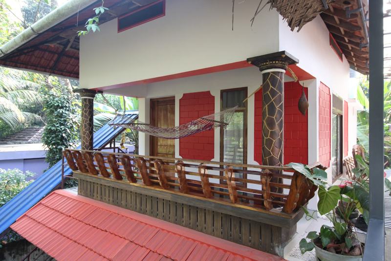 The homestay with its balcony and hammock among coconut palms